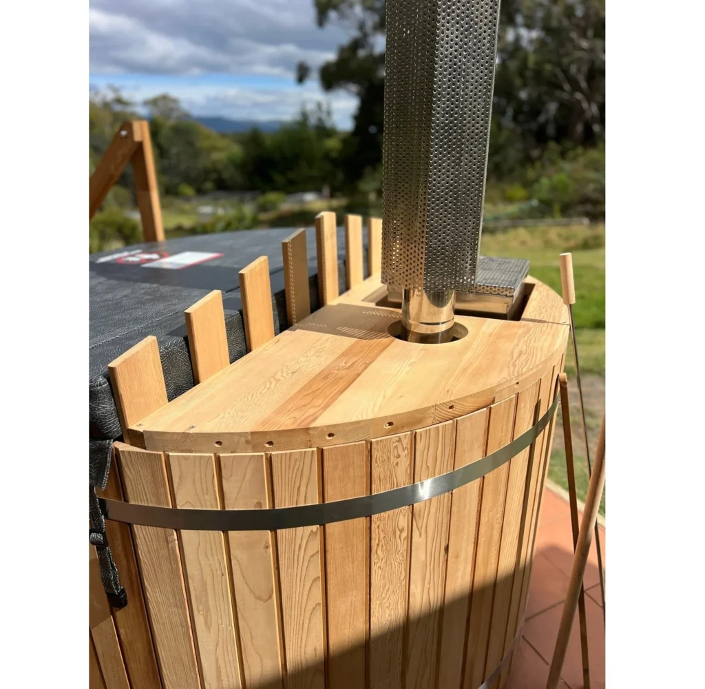 Cedar hot tub with an internal heater and chimney installed outdoors