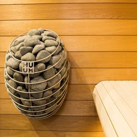 HUUM Drop mounted on a pine sauna wall beside the bench