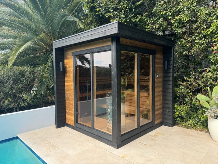 Modern cedar outdoor sauna with black framing and glass doors beside Vaucluse pool area