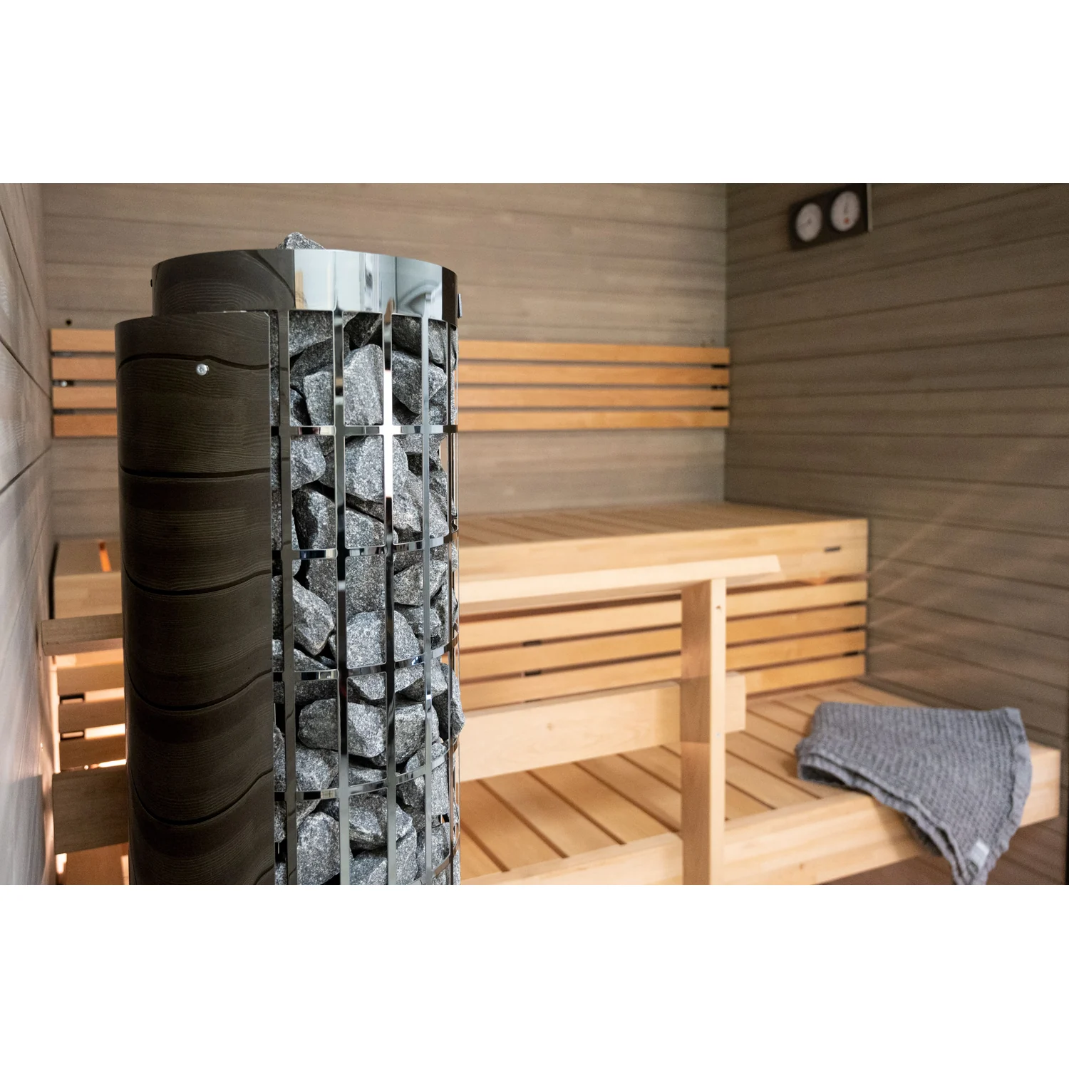Harvia Cilindro PC66E black steel heater beside sauna benches
