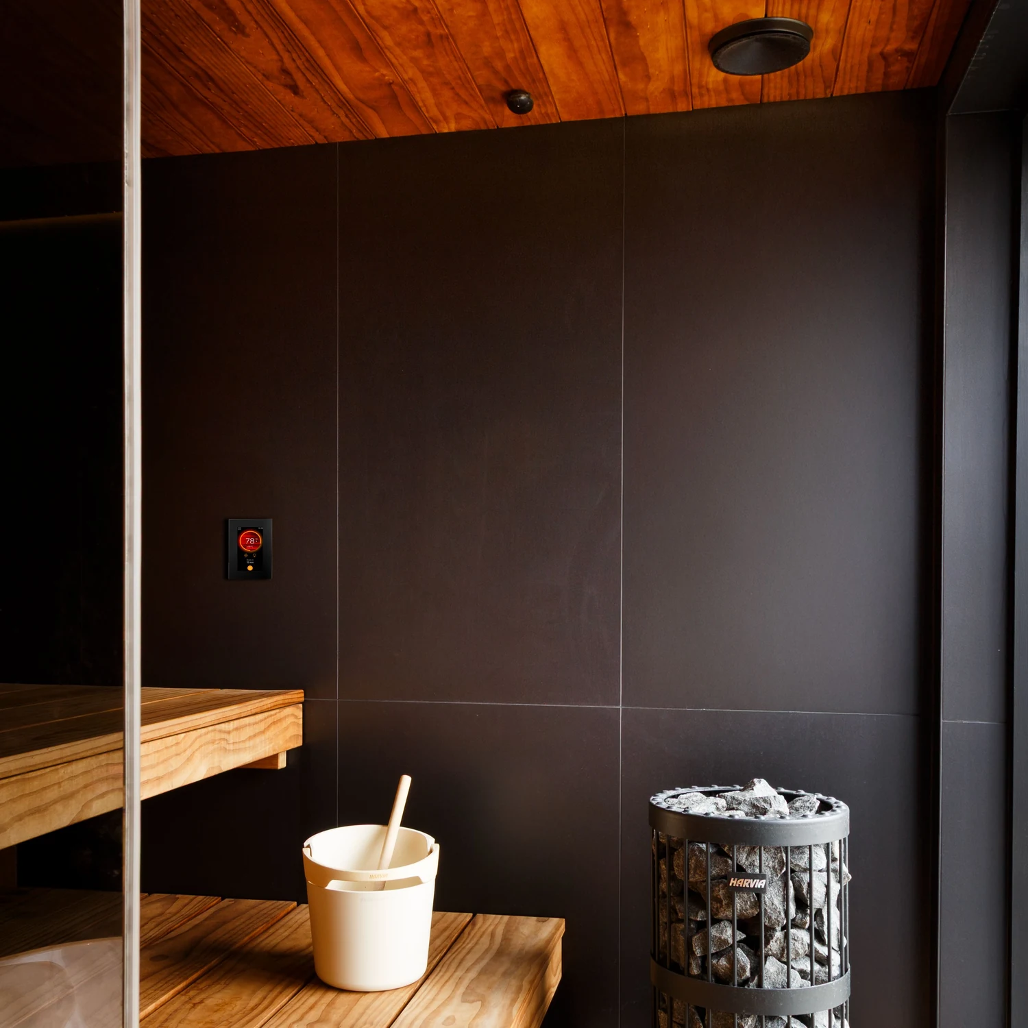 Sauna interior with the Harvia Fenix FX001XW control panel on the wall beside the heater