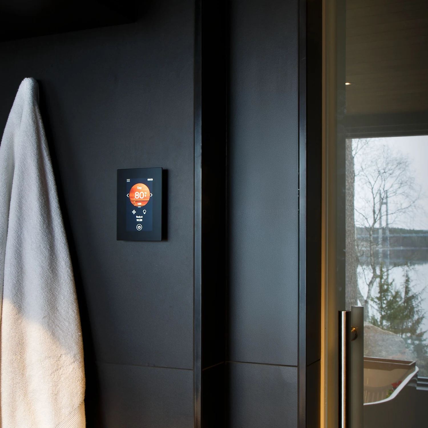 Harvia Fenix FX001XW control panel mounted on a dark wall beside a sauna door