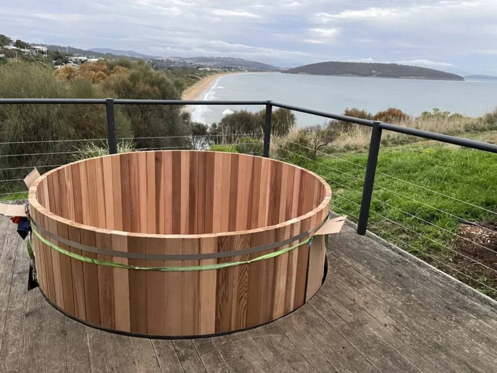 Cedar hot tub installed on a timber deck above the beach