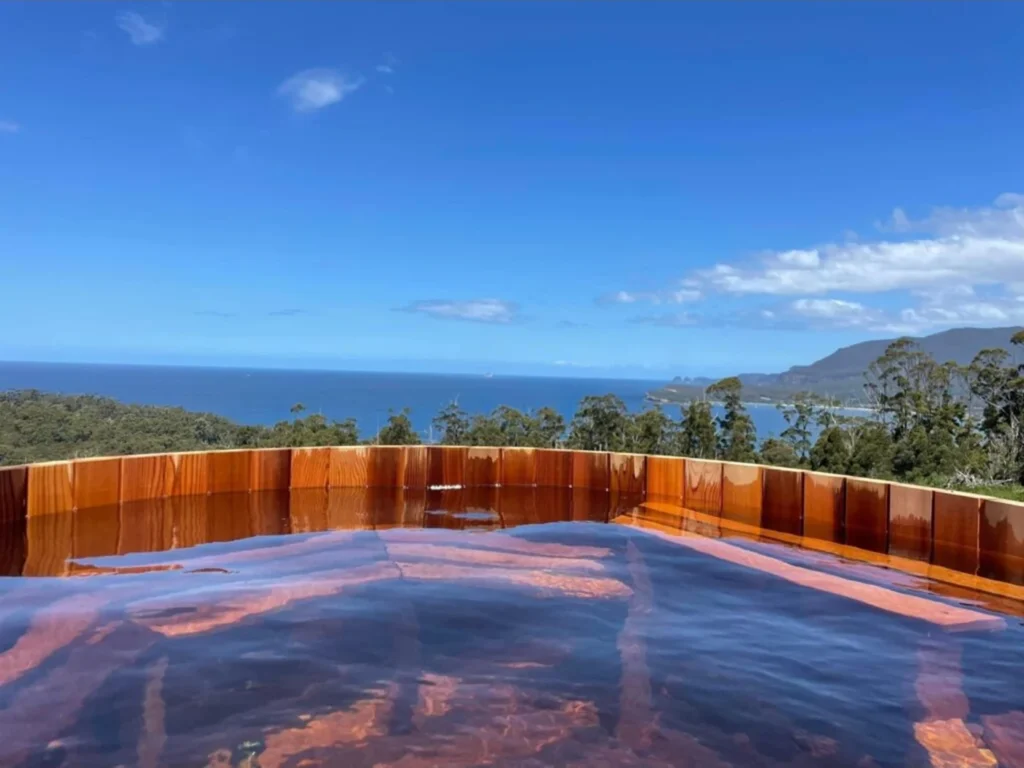Filled cedar hot tub on a deck looking out over the coast