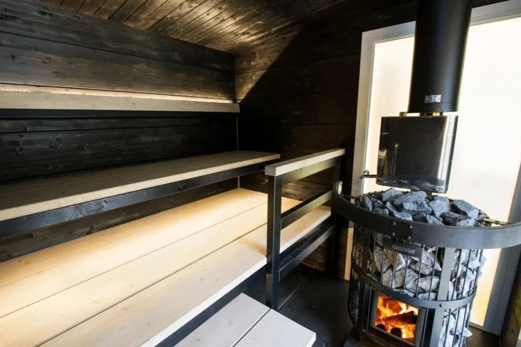 Harvia Legend 150 burning in a dark timber sauna room beside the benches