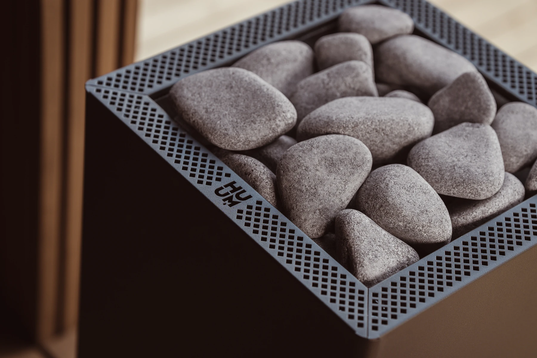 Close up of the sauna stones and perforated black top rim of the HUUM CORE Black