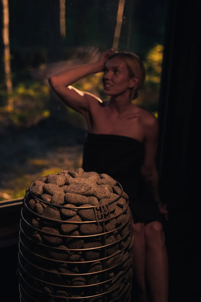 Woman enjoying the heat beside the HUUM HIVE Mini heater